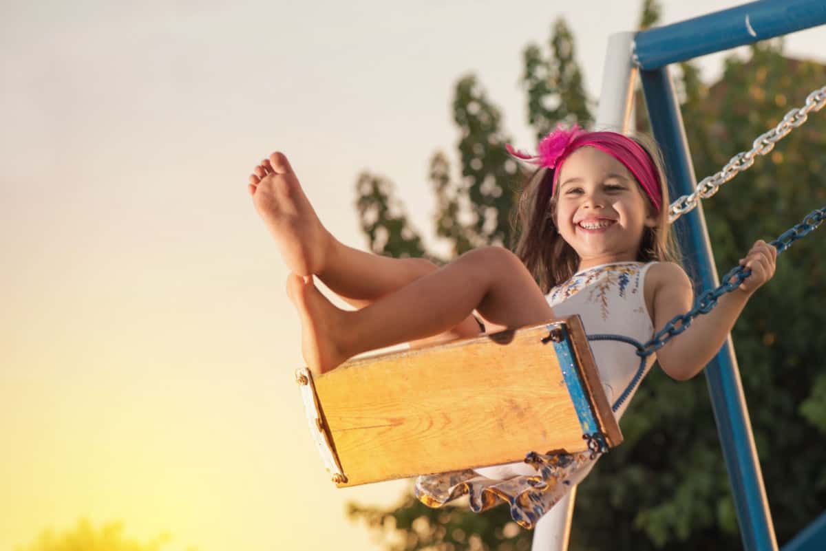 Girl smiling while swinging on swing.
