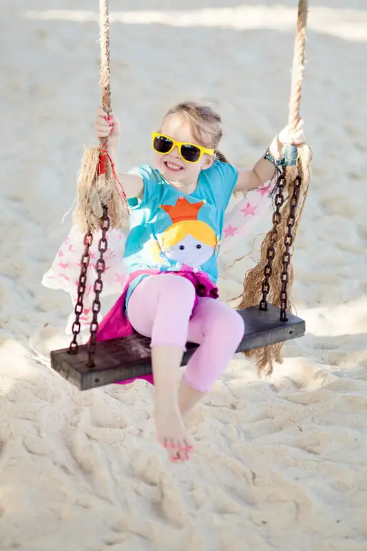 Best Surface Materials For Outdoor Playgrounds 6 Canva Glückliches Mädchen schaukelt am Strand