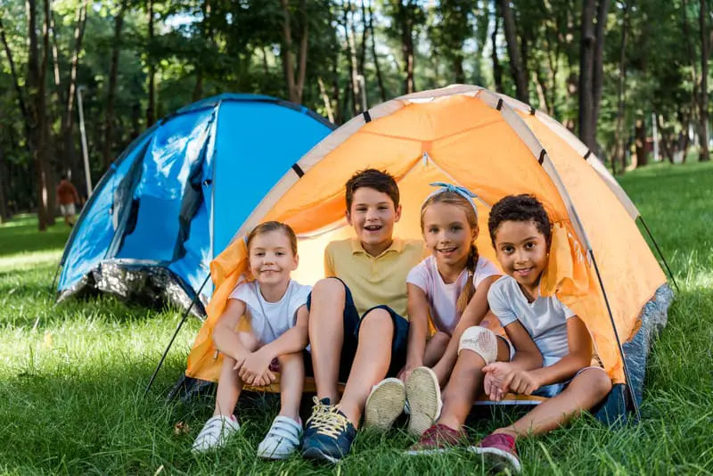 Canva happy multicultural kids smiling while sitting in yellow camp